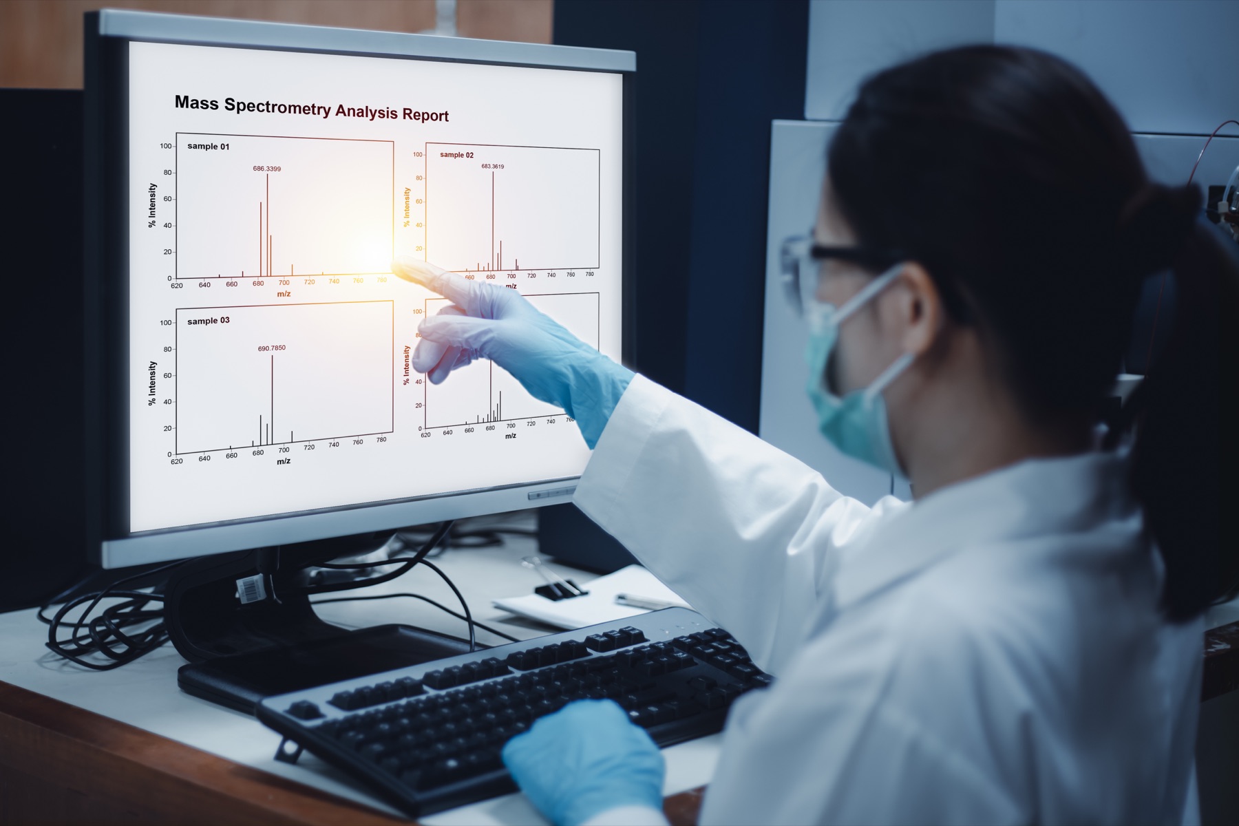 A researcher reviewing mass spectrometry plots on a laboratory computer.